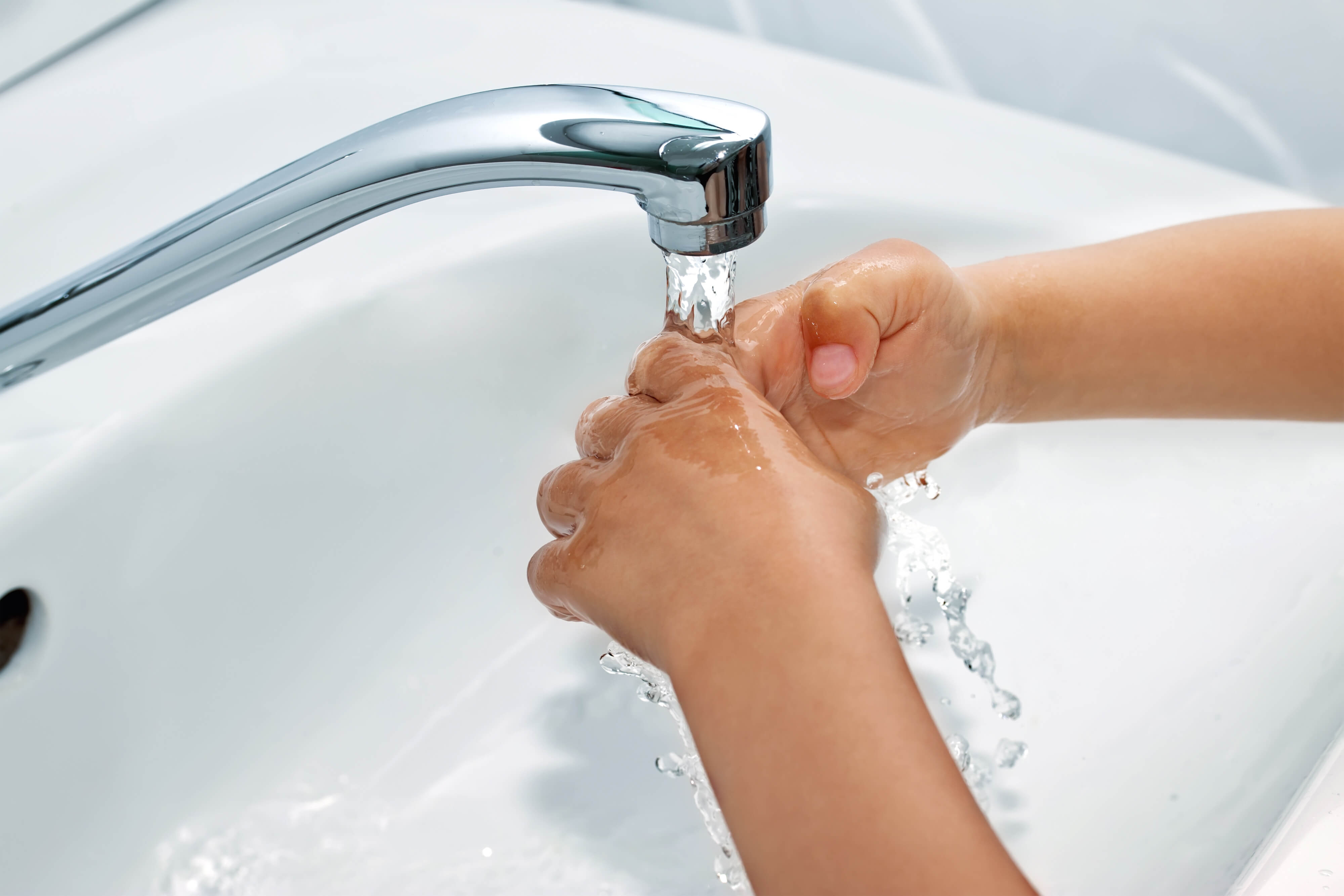 В раковине течет вода. Руки под краном с водой. Руки под струей воды. Мытье рук. Мытье рук под краном.
